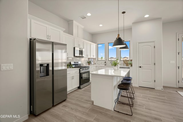 13824 Paseo Bosque Ave, El Paso, TX 79928 - kitchen with stainless steel appliances, white cabinetry, light countertops, a kitchen island, and a breakfast bar