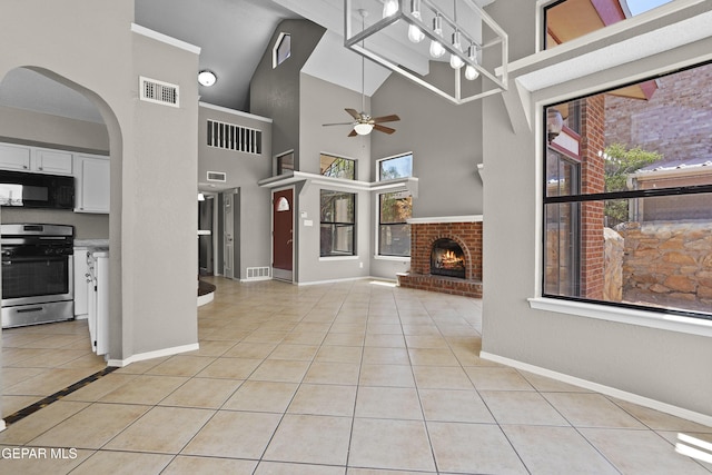 11765 Queens Garden Cir, El Paso, TX 79936 - unfurnished living room with ceiling fan, a brick fireplace, light tile patterned floors, arched walkways, and high vaulted ceiling