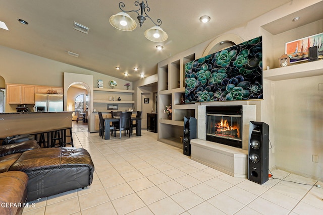 658 John Martin Ct, El Paso, TX 79932 - living room featuring light tile patterned floors, arched walkways, a glass covered fireplace, lofted ceiling, and built in shelves