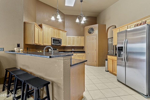 658 John Martin Ct, El Paso, TX 79932 - kitchen with stainless steel appliances, light brown cabinetry, a chandelier, a peninsula, and a high ceiling