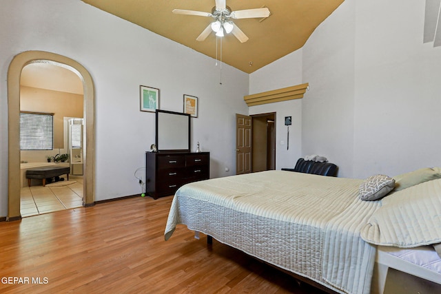 658 John Martin Ct, El Paso, TX 79932 - bedroom featuring wood finished floors, high vaulted ceiling, arched walkways, baseboards, and ensuite bathroom