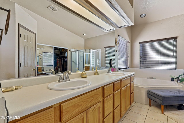 658 John Martin Ct, El Paso, TX 79932 - bathroom featuring tile patterned floors, a shower stall, double vanity, a bath, and a spacious closet