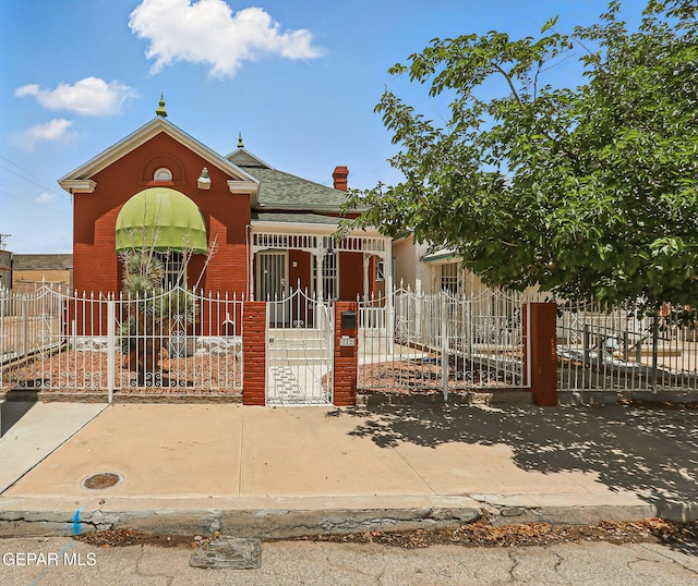 712 N Ochoa St, El Paso, TX 79902 - view of front of home with a fenced front yard, brick siding, a gate, and roof with shingles