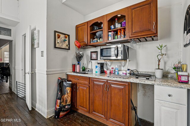 712 N Ochoa St, El Paso, TX 79902 - kitchen with stainless steel microwave, a sink, dark wood-type flooring, brown cabinets, and light stone countertops