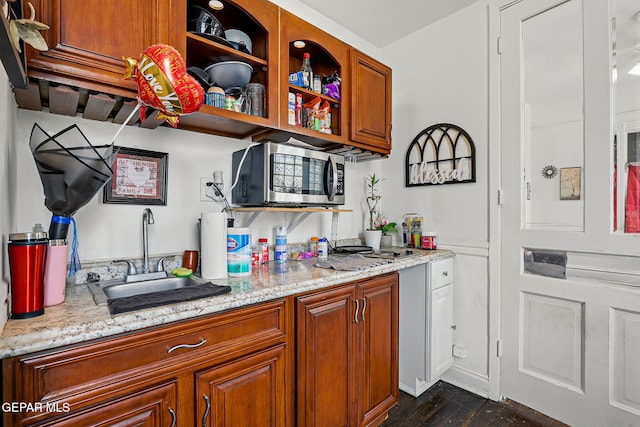 712 N Ochoa St, El Paso, TX 79902 - kitchen featuring stainless steel microwave, a sink, brown cabinets, dark wood finished floors, and light stone counters