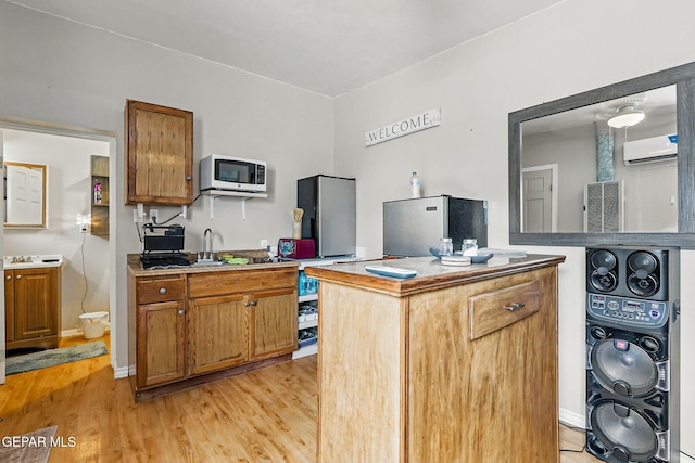 712 N Ochoa St, El Paso, TX 79902 - kitchen featuring a wall mounted air conditioner, white microwave, brown cabinetry, and light wood finished floors