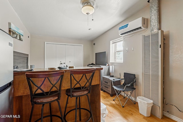 712 N Ochoa St, El Paso, TX 79902 - kitchen featuring a heating unit, an AC wall unit, light wood-style floors, freestanding refrigerator, and a kitchen bar