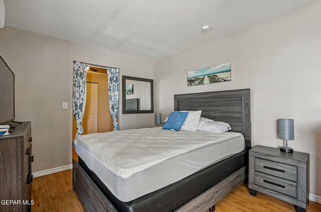 712 N Ochoa St, El Paso, TX 79902 - bedroom featuring wood finished floors, baseboards, and a wall mounted air conditioner