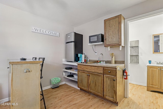 712 N Ochoa St, El Paso, TX 79902 - kitchen featuring a sink, light wood-type flooring, baseboards, and brown cabinets