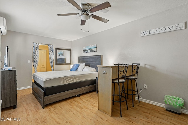 712 N Ochoa St, El Paso, TX 79902 - bedroom with baseboards, light wood-style floors, and a wall mounted air conditioner