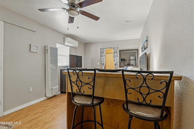 712 N Ochoa St, El Paso, TX 79902 - kitchen featuring a heating unit, light wood-style floors, an AC wall unit, baseboards, and ceiling fan