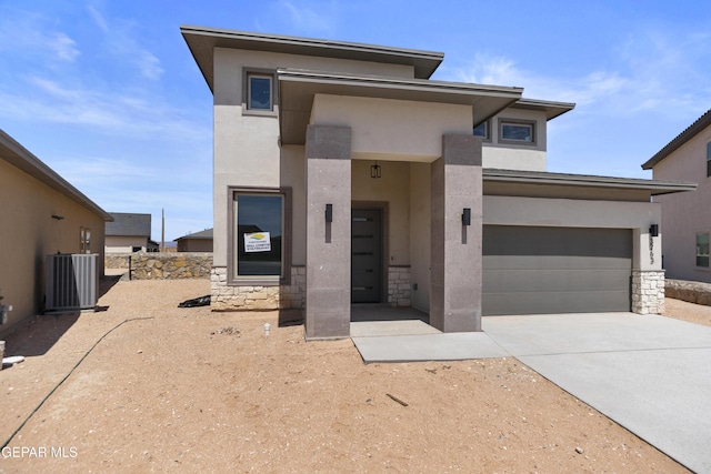 3753 Focus Pl, El Paso, TX 79938 - view of front of house with stone siding, stucco siding, driveway, central AC unit, and an attached garage