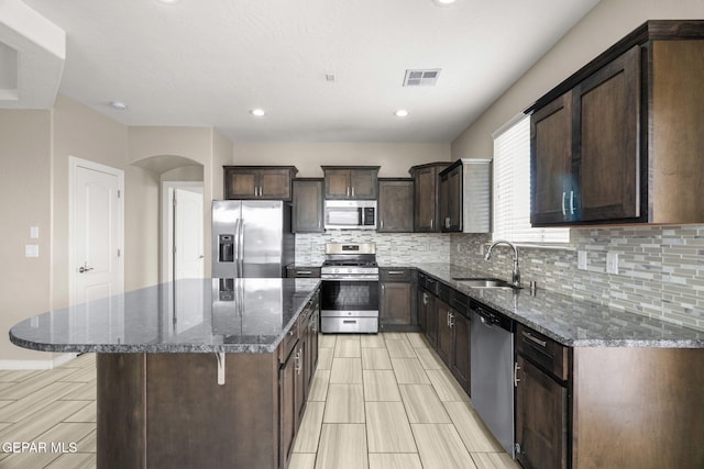 12632 Katherine Brennand Rd, El Paso, TX 79928 - kitchen with appliances with stainless steel finishes, a sink, backsplash, dark brown cabinets, and dark stone countertops