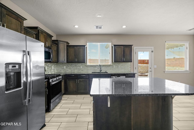 12632 Katherine Brennand Rd, El Paso, TX 79928 - kitchen featuring stainless steel appliances, a sink, dark stone counters, tasteful backsplash, and a center island