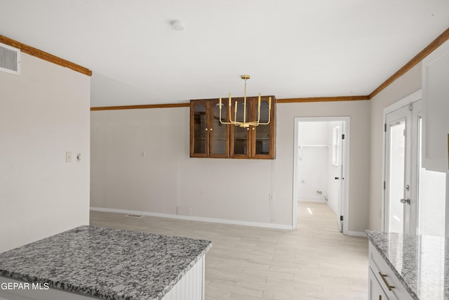 4317 Larchmont Dr, El Paso, TX 79902 - kitchen with a chandelier, light stone counters, baseboards, decorative light fixtures, and glass insert cabinets
