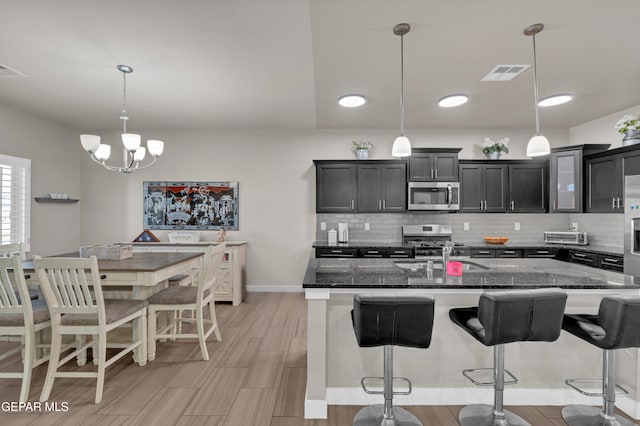 2401 Mike Price Dr, El Paso, TX 79938 - kitchen featuring stainless steel appliances, a sink, a breakfast bar area, and tasteful backsplash