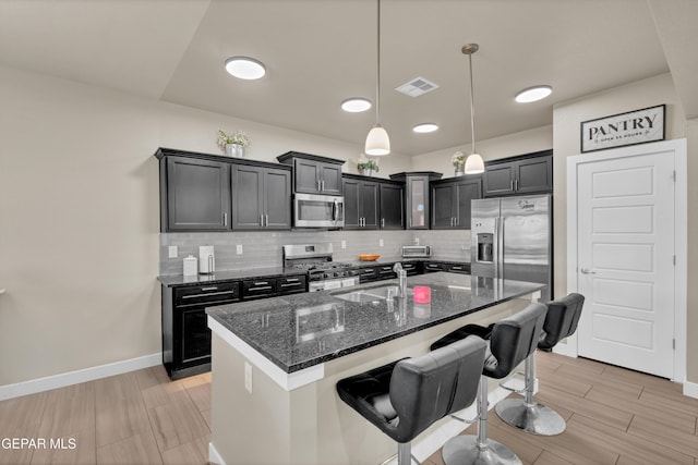 2401 Mike Price Dr, El Paso, TX 79938 - kitchen featuring appliances with stainless steel finishes, a sink, dark stone countertops, a kitchen breakfast bar, and decorative backsplash