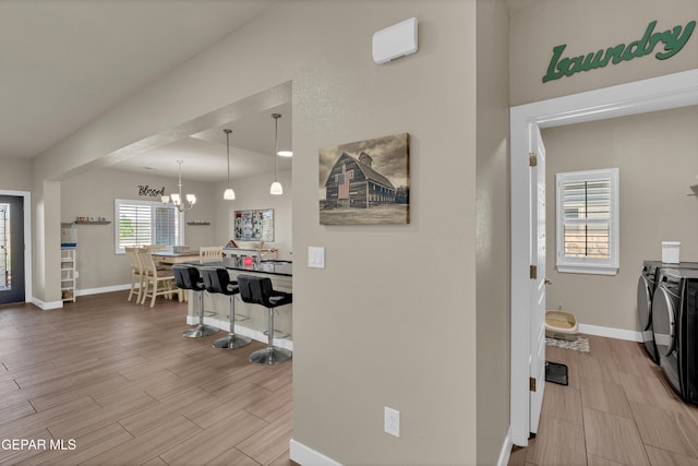 2401 Mike Price Dr, El Paso, TX 79938 - hallway with washing machine and clothes dryer, baseboards, wood tiled floors, and a chandelier