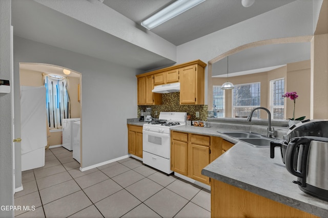 444 Ghost Flower St, Horizon City, TX 79928 - kitchen featuring white range with gas cooktop, under cabinet range hood, independent washer and dryer, backsplash, and light tile patterned floors