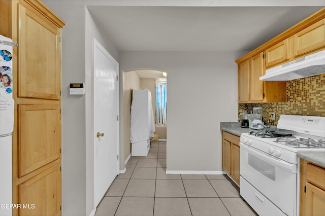 444 Ghost Flower St, Horizon City, TX 79928 - kitchen with white gas range oven, under cabinet range hood, arched walkways, backsplash, and light tile patterned flooring