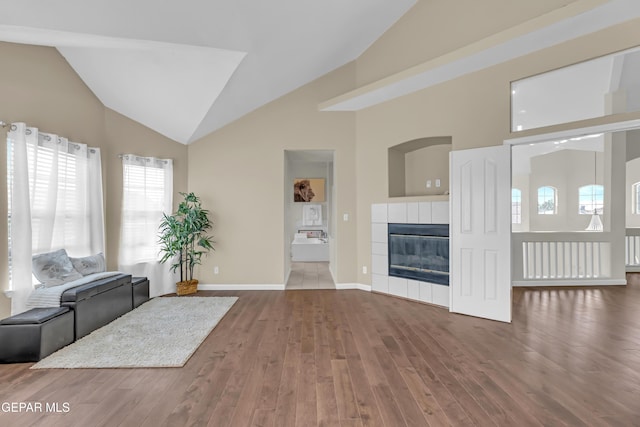 12416 Paseo Largo Cir, El Paso, TX 79928 - unfurnished living room with plenty of natural light, lofted ceiling, wood finished floors, a tiled fireplace, and baseboards