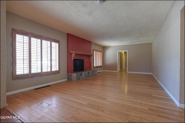 5140 Camino De La Vista Dr, El Paso, TX 79932 - unfurnished living room with a textured ceiling, light wood finished floors, plenty of natural light, a fireplace, and baseboards
