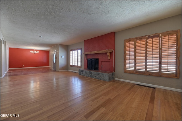 5140 Camino De La Vista Dr, El Paso, TX 79932 - unfurnished living room featuring a textured ceiling, a chandelier, wood finished floors, baseboards, and a brick fireplace