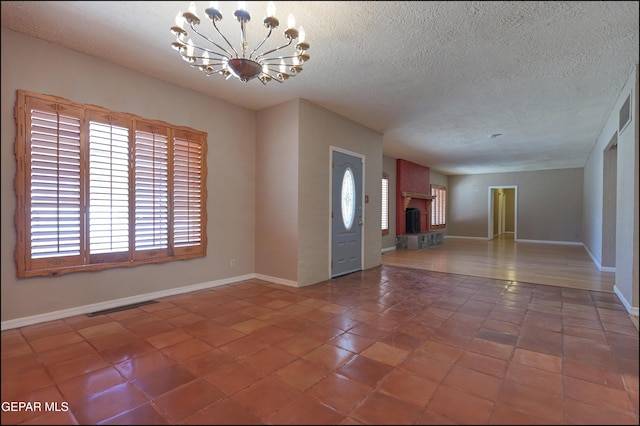 5140 Camino De La Vista Dr, El Paso, TX 79932 - tiled entrance foyer with a chandelier, a textured ceiling, a fireplace, and baseboards