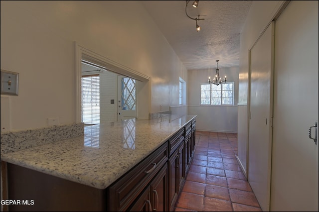 5140 Camino De La Vista Dr, El Paso, TX 79932 - kitchen featuring a chandelier, a textured ceiling, light stone counters, rail lighting, and light tile patterned floors