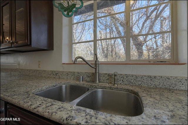5140 Camino De La Vista Dr, El Paso, TX 79932 - kitchen with a sink, dark brown cabinets, light stone counters, and plenty of natural light