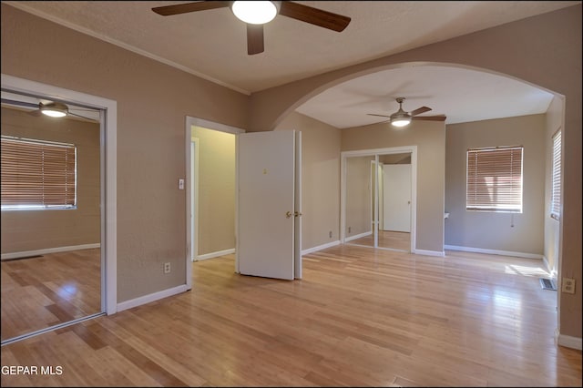 5140 Camino De La Vista Dr, El Paso, TX 79932 - unfurnished bedroom with arched walkways, light wood finished floors, baseboards, and a ceiling fan
