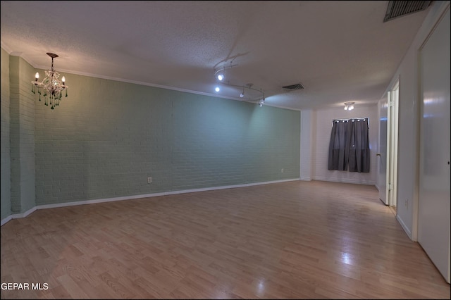 5140 Camino De La Vista Dr, El Paso, TX 79932 - unfurnished room featuring light wood-style flooring, a chandelier, brick wall, a textured ceiling, and baseboards