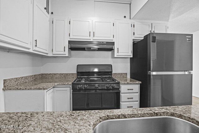 4745 Sierra Madre Dr, El Paso, TX 79904 - kitchen featuring under cabinet range hood, freestanding refrigerator, black gas range, white cabinets, and a textured ceiling