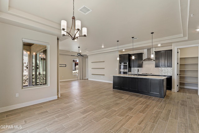 2352 Kolt Ct, El Paso, TX 79911 - kitchen featuring wall chimney range hood, a tray ceiling, open floor plan, light countertops, and double oven
