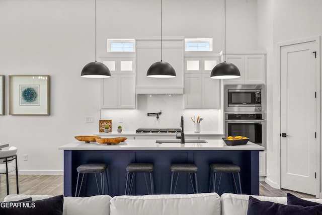 1449 Indigo Sky St, El Paso, TX 79928 - kitchen with stainless steel appliances, a sink, light countertops, white cabinets, and a kitchen bar