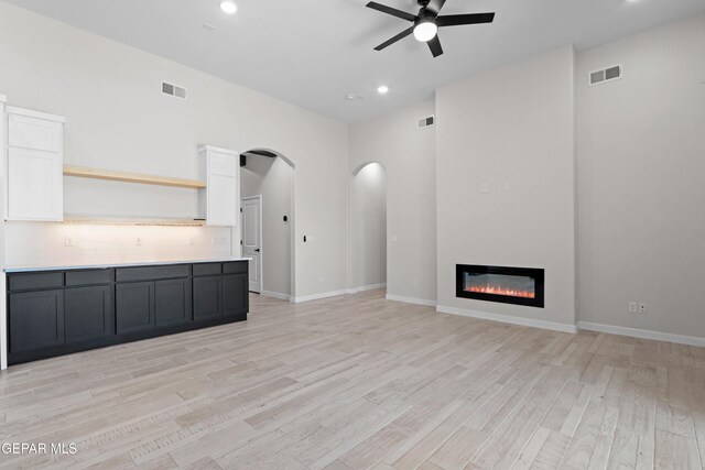 13368 Coldham St, El Paso, TX 79928 - unfurnished living room featuring ceiling fan, arched walkways, light wood-style floors, recessed lighting, and a glass covered fireplace