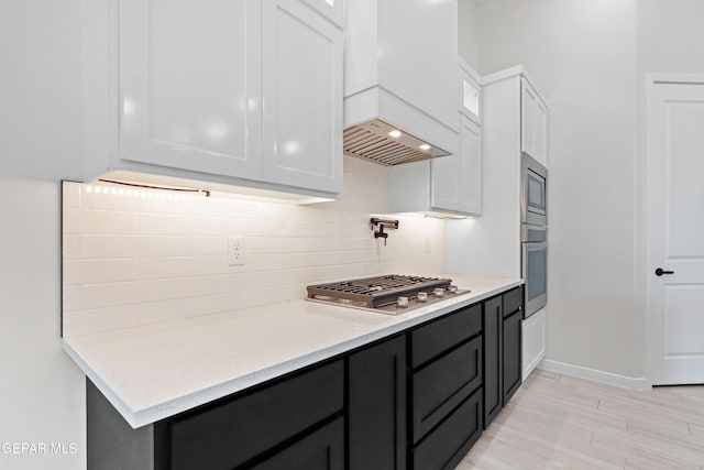 13368 Coldham St, El Paso, TX 79928 - kitchen featuring custom range hood, appliances with stainless steel finishes, decorative backsplash, white cabinets, and glass insert cabinets