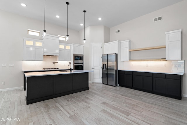 13368 Coldham St, El Paso, TX 79928 - kitchen featuring appliances with stainless steel finishes, a sink, open shelves, light wood finished floors, and decorative backsplash