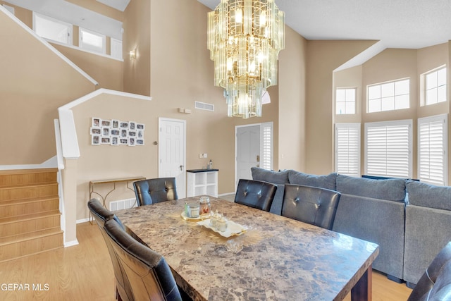 6800 Canyon Run Dr, El Paso, TX 79912 - dining room featuring stairs, a towering ceiling, light wood-style flooring, a chandelier, and baseboards