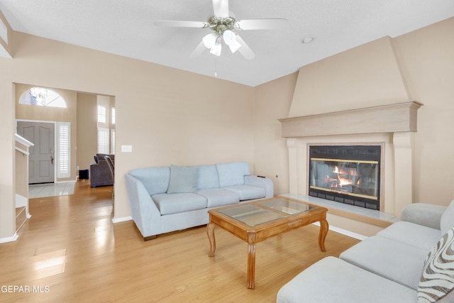 6800 Canyon Run Dr, El Paso, TX 79912 - living area with light wood-type flooring, a ceiling fan, a glass covered fireplace, and baseboards