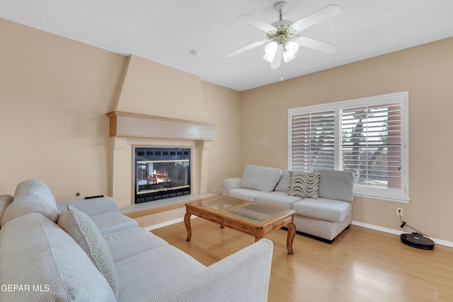 6800 Canyon Run Dr, El Paso, TX 79912 - living area featuring light wood finished floors, ceiling fan, a glass covered fireplace, baseboards, and a textured ceiling