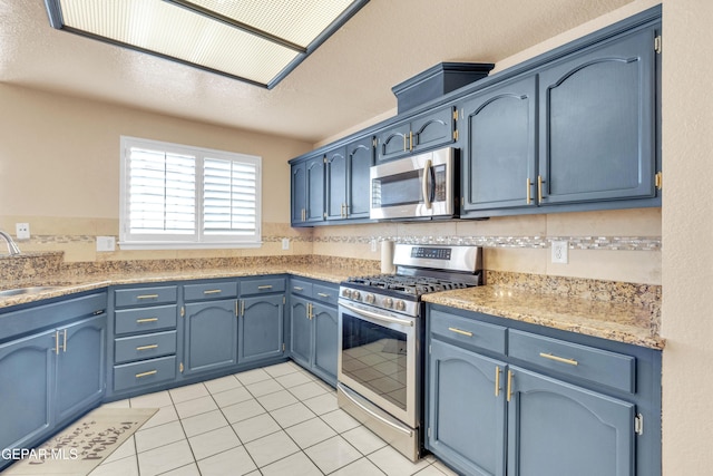 6800 Canyon Run Dr, El Paso, TX 79912 - kitchen featuring appliances with stainless steel finishes, a sink, blue cabinetry, and light tile patterned floors