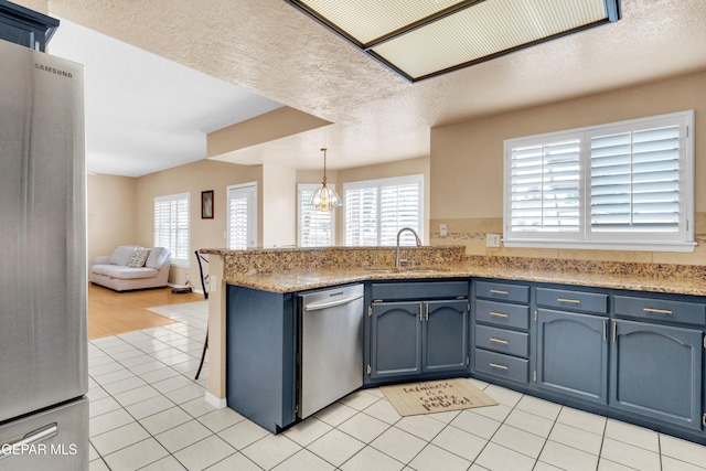 6800 Canyon Run Dr, El Paso, TX 79912 - kitchen with appliances with stainless steel finishes, a peninsula, a sink, blue cabinets, and a textured ceiling