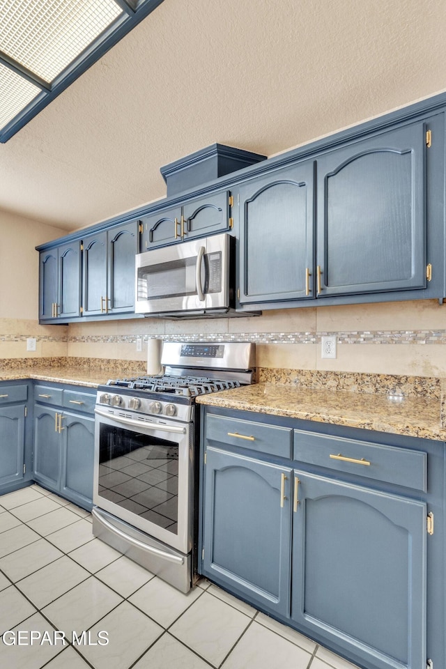 6800 Canyon Run Dr, El Paso, TX 79912 - kitchen with appliances with stainless steel finishes, blue cabinets, light tile patterned floors, and a textured ceiling