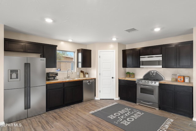 628 Milo Dr, El Paso, TX 79927 - kitchen with appliances with stainless steel finishes, a sink, wood finish floors, light countertops, and recessed lighting
