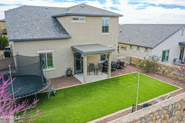 7517 Red Cedar Dr, El Paso, TX 79911 - back of house featuring a trampoline, stucco siding, a shingled roof, and a patio area