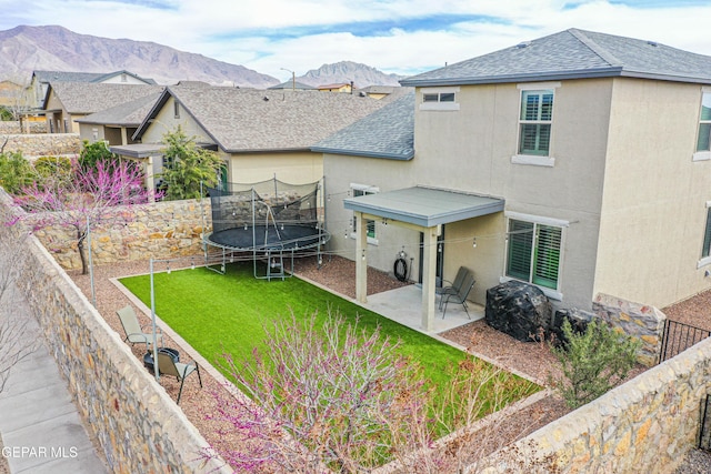 7517 Red Cedar Dr, El Paso, TX 79911 - back of house with a patio area, a trampoline, a shingled roof, stucco siding, and a mountain view