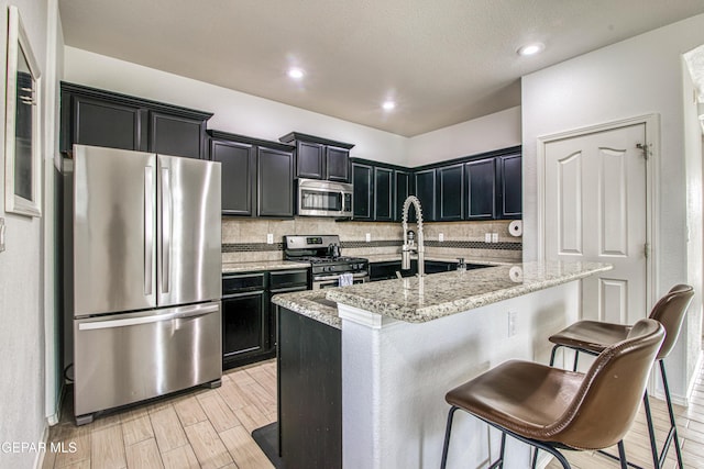 7517 Red Cedar Dr, El Paso, TX 79911 - kitchen featuring appliances with stainless steel finishes, dark cabinetry, a breakfast bar area, and recessed lighting