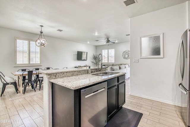 7517 Red Cedar Dr, El Paso, TX 79911 - kitchen with stainless steel appliances, a sink, baseboards, wood finish floors, and pendant lighting