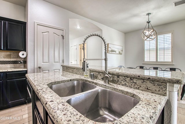 7517 Red Cedar Dr, El Paso, TX 79911 - kitchen featuring a sink, dark cabinets, light wood-type flooring, light stone countertops, and pendant lighting